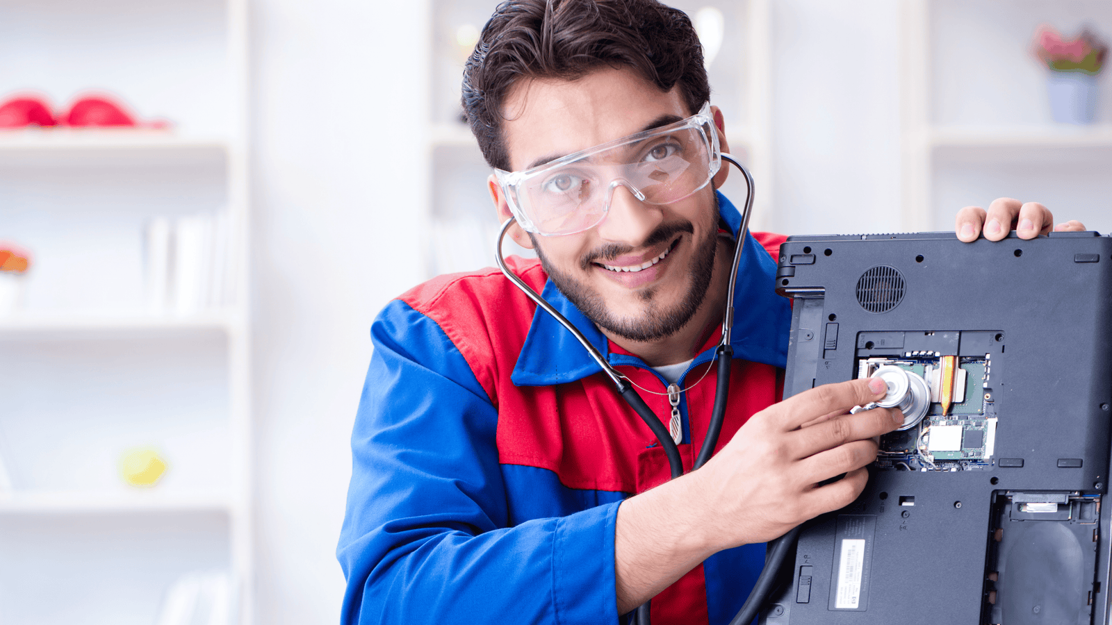 Technician in safety gear playfully checks a laptop's internals, ideal for bulk refurbished laptops for sale.